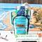 The front curved zipper pouch of a blue, green and white leaf print water bottle bag is displayed while it holds a 40 oz Stanley Quencher.